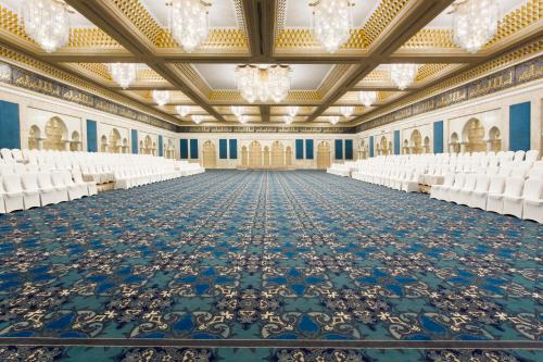 an empty banquet hall with white chairs and a large ceiling at The Regency Hotel Kuwait in Kuwait