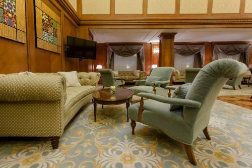 a living room with couches and chairs and a television at The Regency Hotel Kuwait in Kuwait