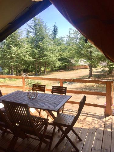 a table and chairs on a deck with a view of a field at Domaine de la Vitarelle Glamping in Villanière