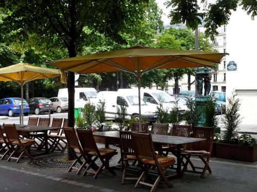 a group of tables and chairs under an umbrella at Hôtel Roi René in Paris