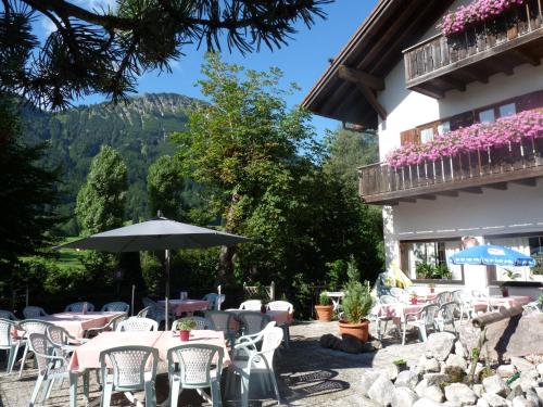 a patio with tables and chairs and an umbrella at Hotel Pfrontener Hof in Pfronten