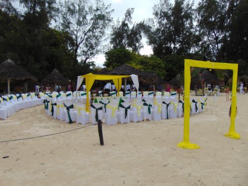 a row of chairs on a beach with yellow poles at Scorpio Villas Resort in Malindi