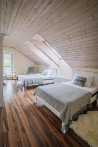 two beds in a large room with wooden ceilings at Väike-Mere Villa in Haapsalu