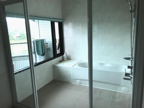 a white bathroom with a shower and a sink at Yin Mama Warm House in Yilan City
