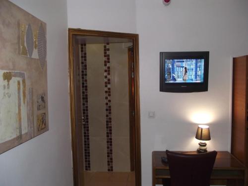 a room with a mirror and a table and a television at Le Nouvel Hôtel du Théâtre in Paris