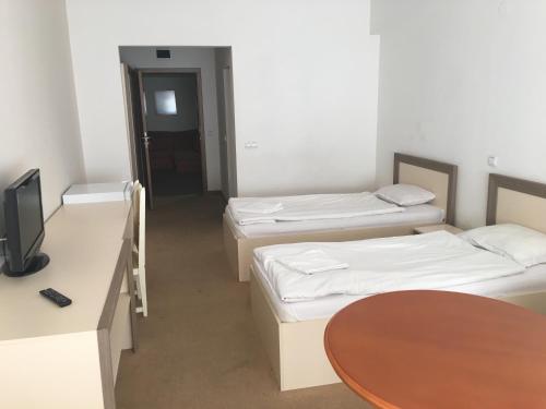 a room with three beds and a table and a tv at Hostel Elena in Sofia