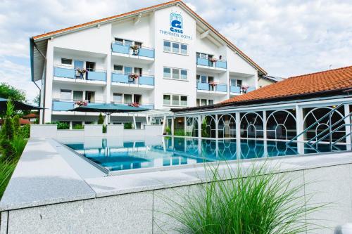 a hotel with a swimming pool in front of a building at Thermalhotel Gass in Bad Füssing