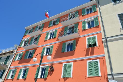 an orange building with green windows and a flag at Hotel San Pietro Chiavari in Chiavari
