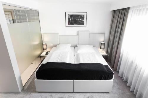 1 Schlafzimmer mit einem Bett, 2 Tischen und einem Spiegel in der Unterkunft Pearl Design Hotel - Frankfurt City in Frankfurt am Main