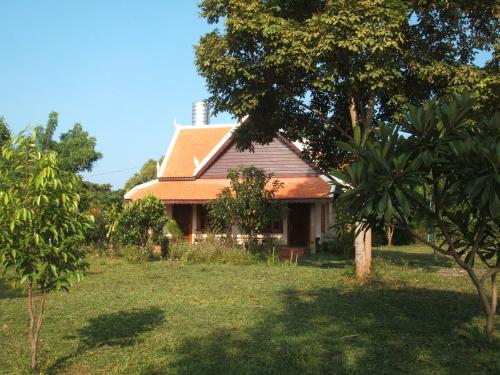 una casa con un árbol delante en Green Plateau Lodge, en Banlung