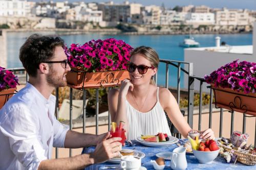 a man and a woman sitting at a table with food at Hotel Palazzo Papaleo in Otranto