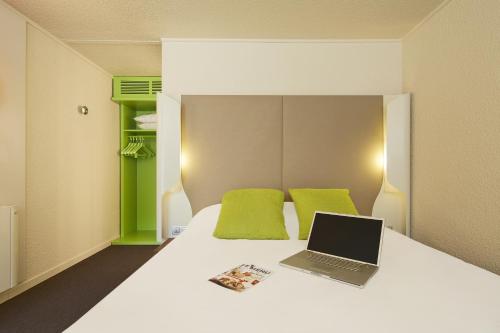 a bedroom with a bed with a laptop on it at Campanile Hotel Compiegne in Compiègne