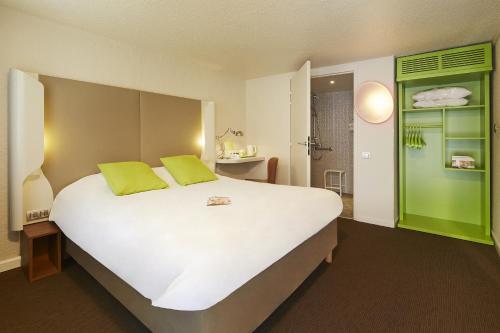 a bedroom with a large white bed with green accents at Campanile Hotel Compiegne in Compiègne