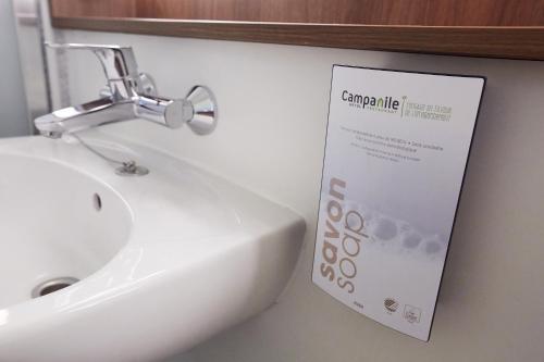 a white sink and a sign on a wall at Campanile Hotel Compiegne in Compiègne