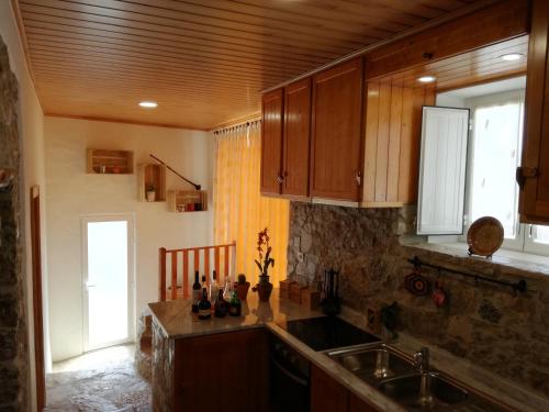 uma cozinha com armários de madeira, um lavatório e uma janela em Casa da Figueirinha em Casais dos Monizes