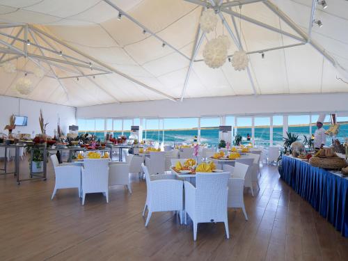 een eetkamer met witte tafels en witte stoelen bij Dana Beach Resort in Half Moon Bay