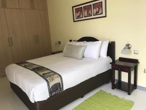 a bedroom with a large white bed with a night stand at Stoneridge Estate in Lusaka