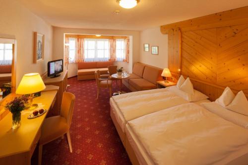 Habitación de hotel con cama y sala de estar. en Hotel Büntali, en Galtür