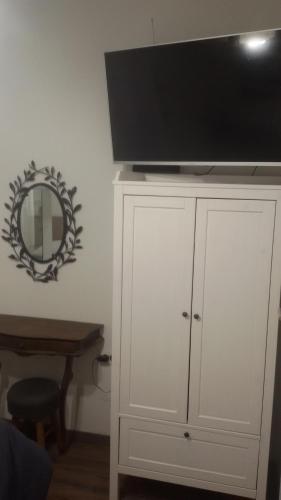 TV en la parte superior de un armario blanco con espejo en Room Mate Split, en Split