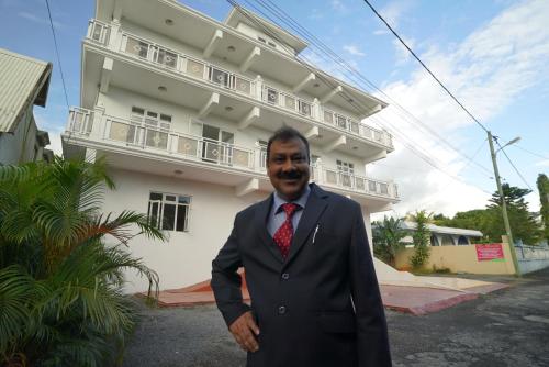 a man in a suit and tie standing in front of a building at La Dorade in Trou aux Biches