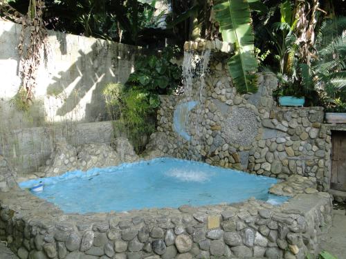 a hot tub in a stone wall with a waterfall at Pousada Caúca in Abraão