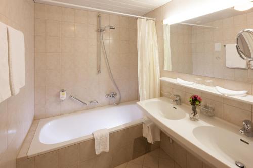 a bathroom with a tub and a sink and a mirror at Hotel Büntali in Galtür