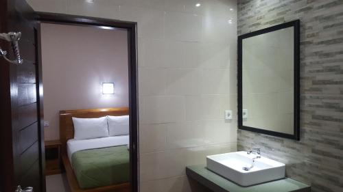 a bathroom with a sink and a mirror and a bed at Umayuri Inn in Ubud