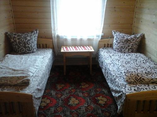 Habitación pequeña con 2 camas y ventana en Romashka Guest House, en Yablunytsya