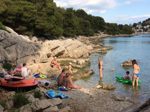 a group of people sitting in the water on a beach at Apartman Tribunj in Tribunj