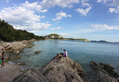 a group of people standing on rocks in the water at Apartman Tribunj in Tribunj
