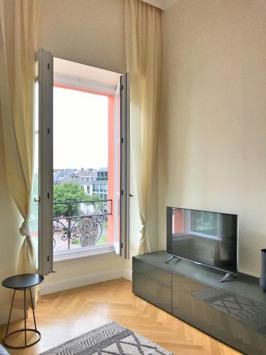 a living room with a television and a large window at Osteiner Hof by The Apartment Suite in Mainz