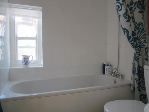 a bathroom with a tub and a window and a toilet at Carpenter's Cottage in Pocklington