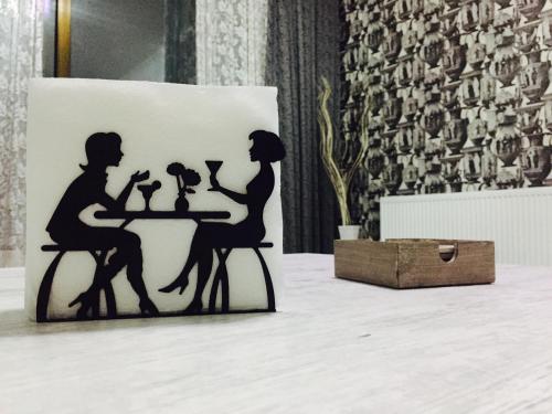 a silhouette of a couple sitting at a table with wine glasses at AIA Apartment in Kutaisi