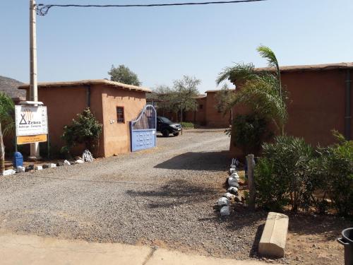 a gravel driveway with a gate and a building at Camping Auberge Zebra in Ouzoud