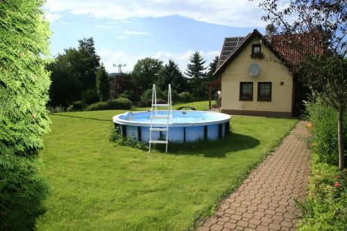 a pool in a yard next to a house at Taneček - malý apartmán u rodinného domu in Stvolínky