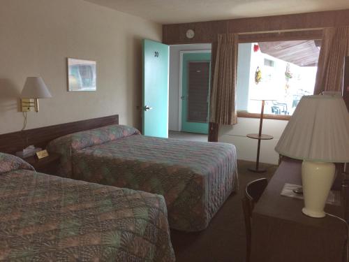 a hotel room with two beds and a lamp and a window at Crystal Sands Motel in Wildwood