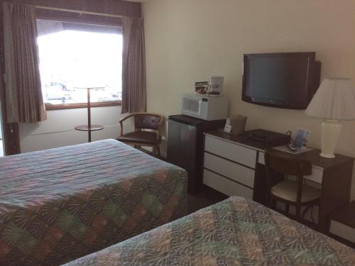 a hotel room with two beds and a flat screen tv at Crystal Sands Motel in Wildwood