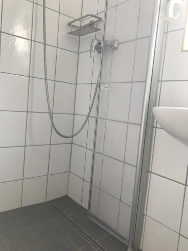 a shower in a white tiled bathroom with a sink at Haus Heverstrom in Westerhever