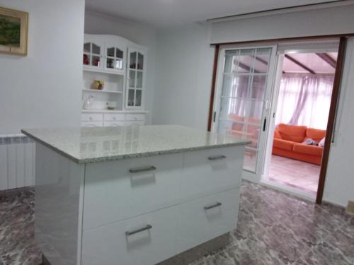 ポルトノボにあるApartamentos Barrosaのキッチン(白いカウンタートップ、オレンジのソファ付)