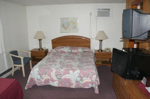a bedroom with a bed and a flat screen tv at Northern Peaks Motor Inn in Gorham
