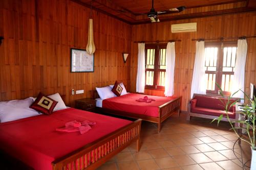 BanlungにあるGreen Plateau Lodgeのベッドルーム1室(ベッド2台、椅子、窓付)
