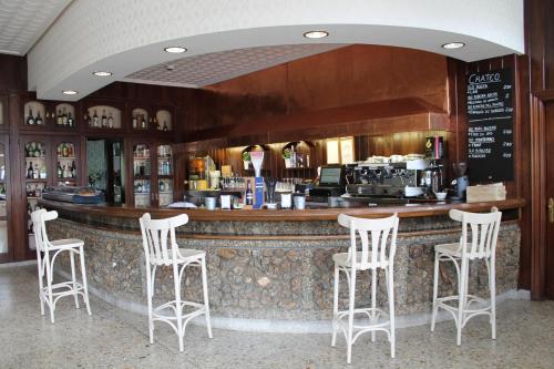 bar z czterema białymi stołkami w restauracji w obiekcie Hotel Montero w mieście Mondoñedo
