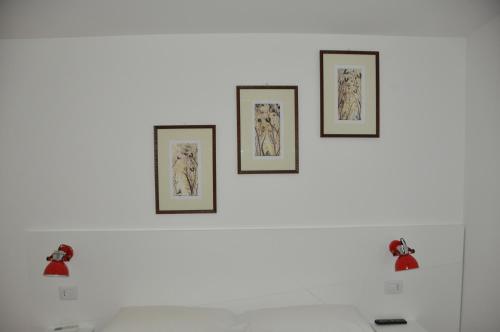 four pictures on a white wall above a bed at Porta Barsento in Putignano