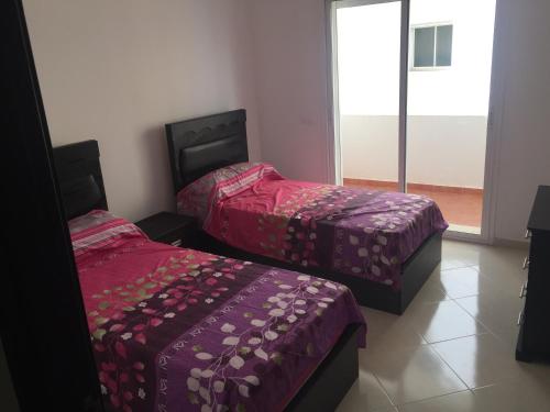two beds in a room with purple covers on them at Appartement De Luxe A Wilaya De Tetouan in Tetouan