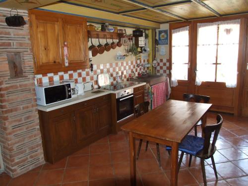 eine Küche mit Holzschränken, einem Tisch, einem Tisch und Stühlen in der Unterkunft Chambre d'Hôtes "Au Vigneron" in Triembach-au-Val
