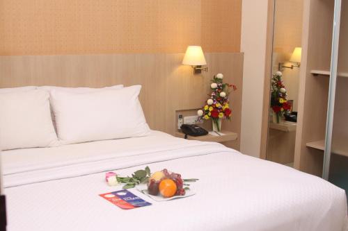 a bed with a plate of fruit and a christmas tree at Rio City Hotel in Palembang