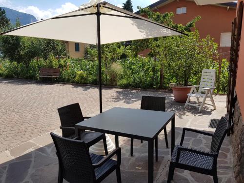 stół i krzesła z parasolem na patio w obiekcie Appartamento Lido w mieście Levico Terme