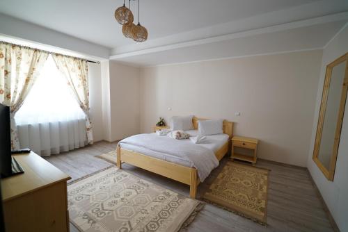 a white bedroom with a bed and a window at Casa Bunicii in Moisei