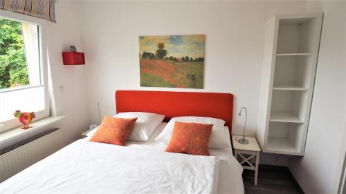 a bedroom with a white bed with an orange headboard at Apartment Alleestraße in Büsum