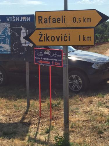 a street sign in front of a car at Apartments Villa Mimi in Višnjan